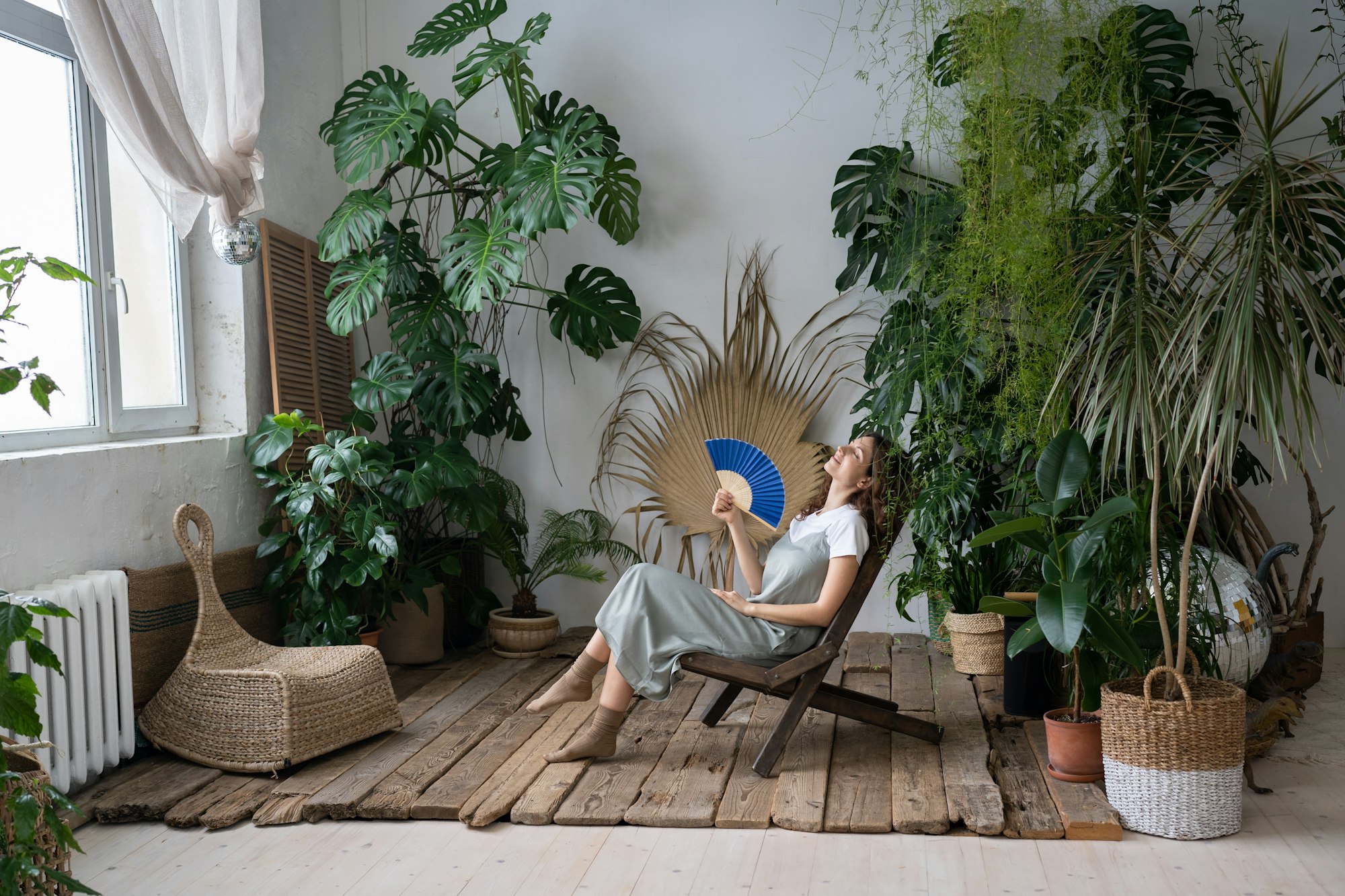 Stress relief after work. Relaxed young girl spend time in cozy indoor garden with monstera plant