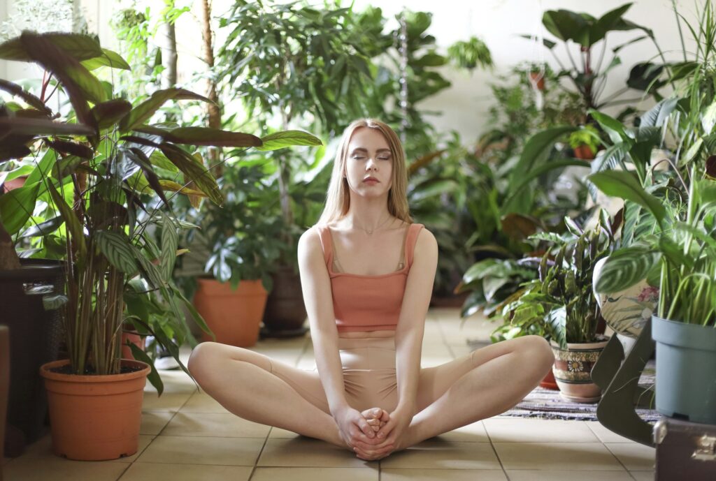 Calm woman doing yoga among plants