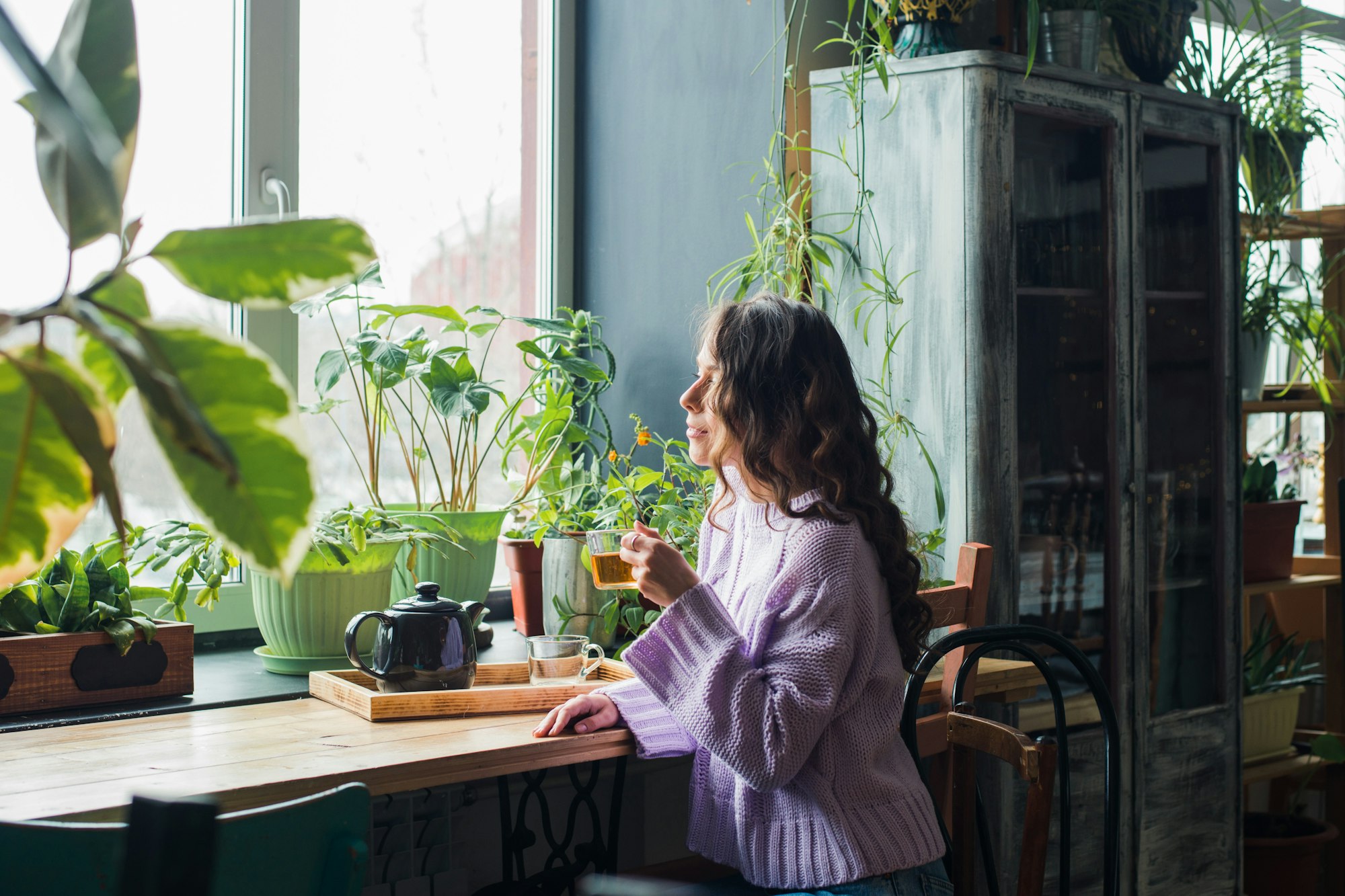 woman drink tea at home plants around